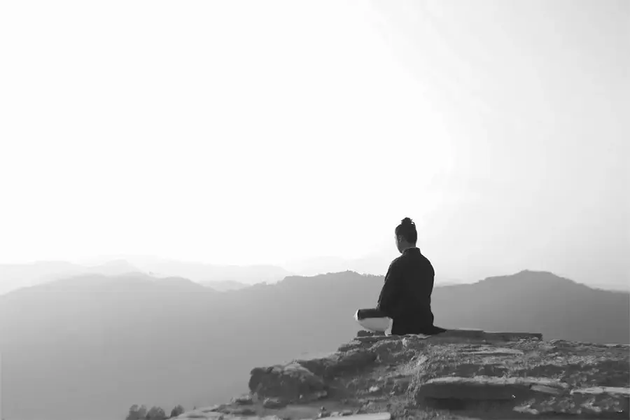 Taoist monk meditating in mountains