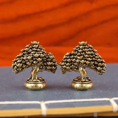 Two brass fortune trees with stacked ingot crowns standing on an open book