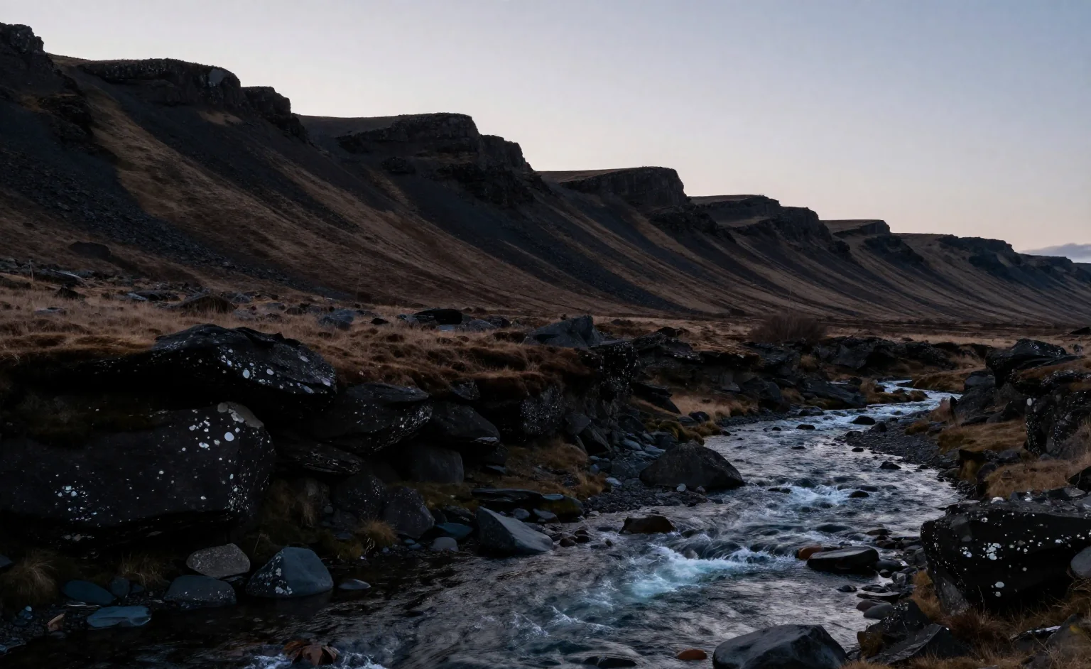 Yin and yang in nature shown by a dark mountain ridge and clear moving water in a wide dawn landscape